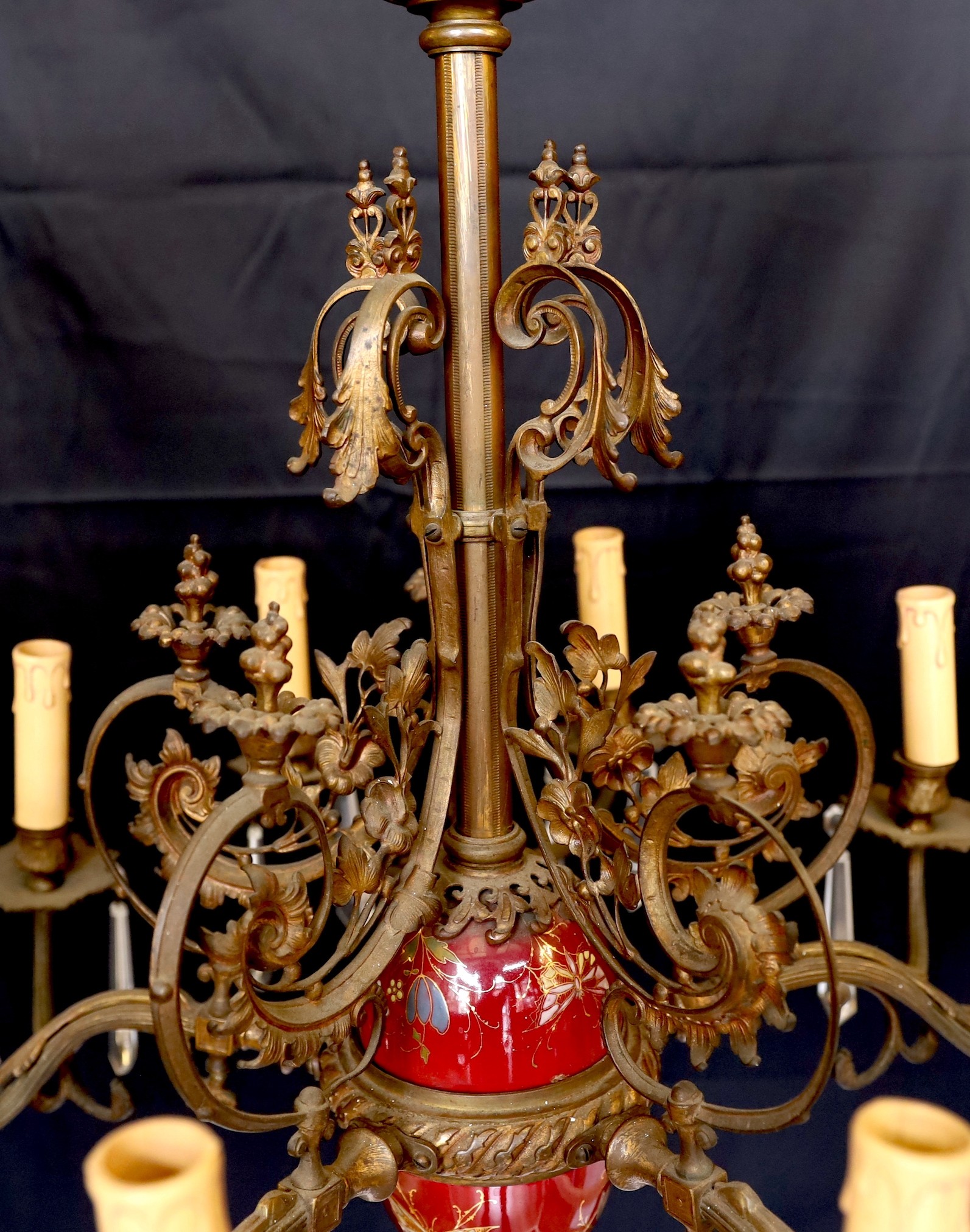 A Victorian bronze ten light gasolier with ornate scrolling foliate frieze and central ceramic stem, hung with spear shaped drops, later fitted for electricity, height 92cm. width 60cm
